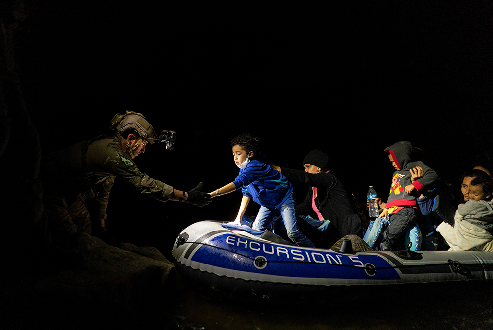 Migrants seeking asylum in the U.S. attempt to get off an inflatable raft with the help of a Texas Ranger officer April 5, 2021, in Roma, Texas, after they crossed the Rio Grande from Mexico. (CNS/Go Nakamura, Reuters) Migrants seeking asylum in the U.S. attempt to get off an inflatable raft with the help of a Texas Ranger officer April 5, 2021, in Roma, Texas, after they crossed the Rio Grande from Mexico. (CNS/Go Nakamura, Reuters)